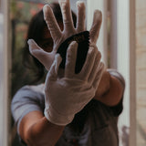 a palm sized black guasha tool (made from volcanic and metero matter) shaped into an abstract shape with one side ridged.  The tool is held next to an open face hand to show the size.