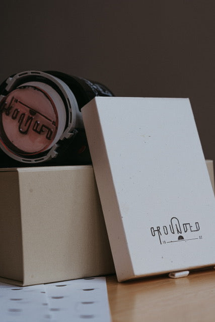 A packaging picture - the cardboard shipping box.  A stamp on top of it.  A drawer box for the guasha next to it.  Sitting on branded tissue paper.